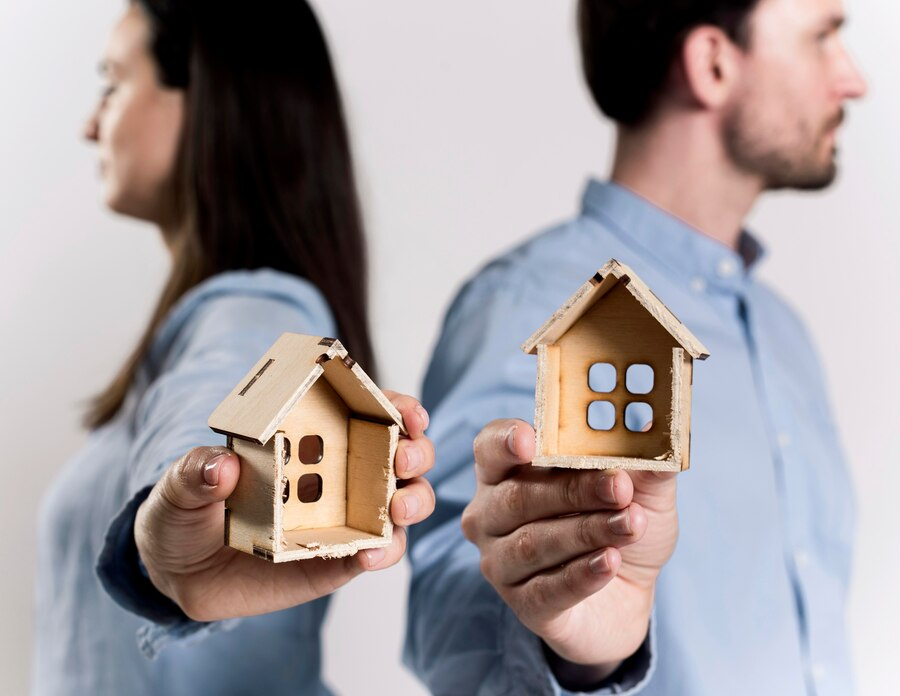 Couple holding wooden half-house.