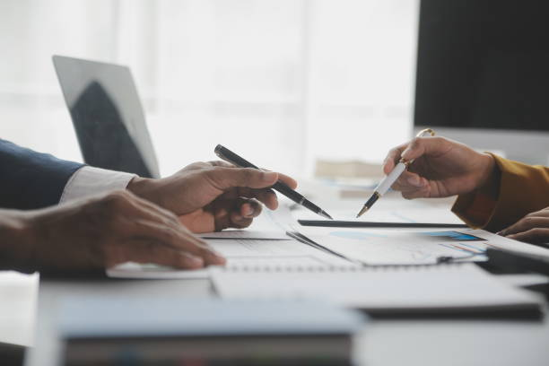 Two people with pens pointing at a document.